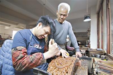 中國(guó)僑網(wǎng)胡敏強(qiáng)（右）在指導(dǎo)年輕人雕刻紅木。 